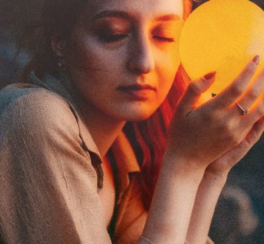 Woman holding glowing orange orb near her face