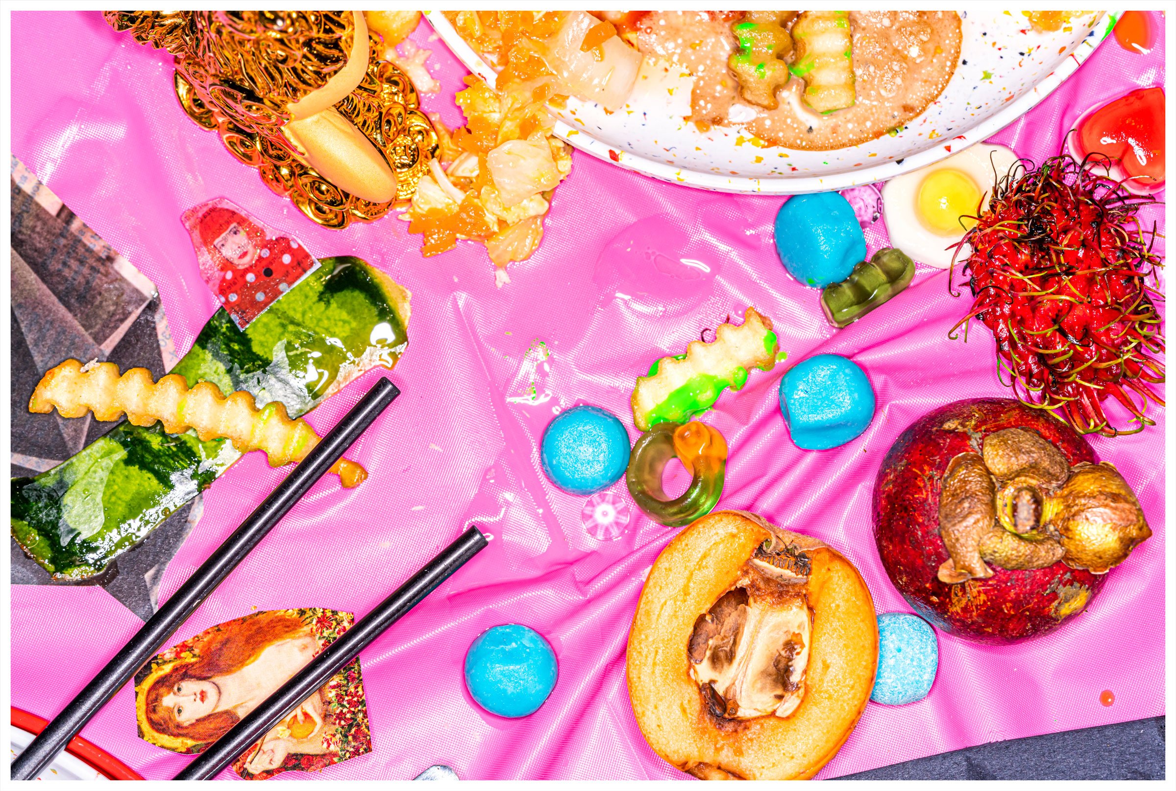 Busy image with mix of food and candy on a pink table